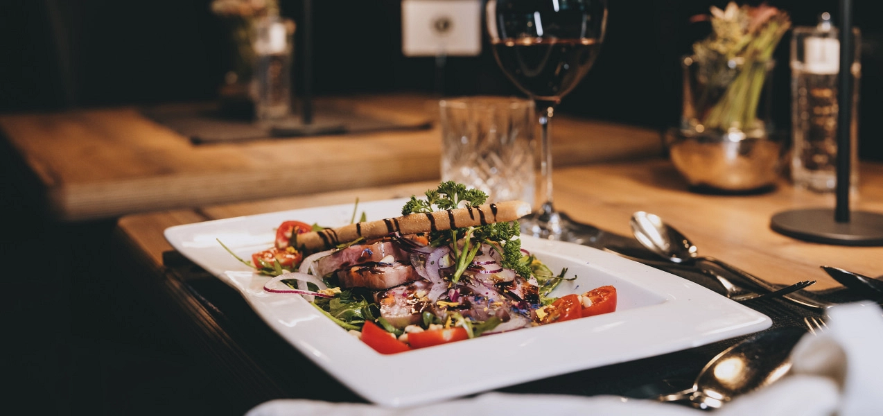 Eleganter Teller mit gegrilltem Fleisch, Gemüse und einem Glas Wein