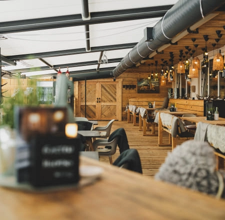 Gemütliche Terrasse mit Tischen und Holzverkleidung